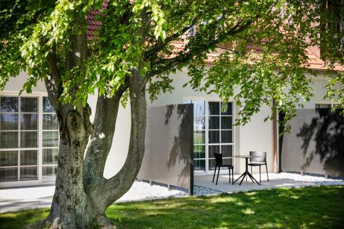 a table and chair under a tree in a yard at Hotel Spitzerberg by b-smart in Hundsheim