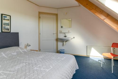 1 dormitorio con cama y lavamanos en vakantiehuis op terschelling, en Baaiduinen