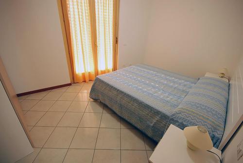 een kleine slaapkamer met een bed en een tegelvloer bij Residence Seaside in Tortoreto Lido