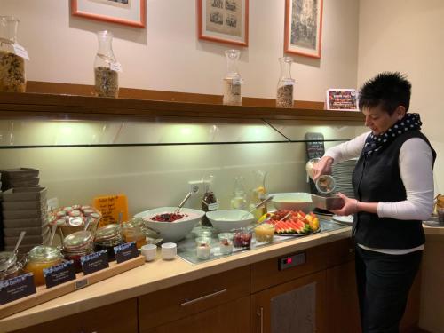 a woman standing in a kitchen preparing food at Altstadthotel Arte in Fulda