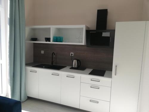 a white kitchen with a sink and a microwave at APARTAMENTY POSEJDON in Świnoujście