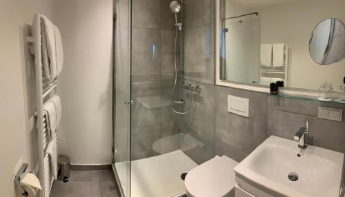 a bathroom with a shower and a toilet and a sink at Congress Hotel am Stadtpark in Hannover