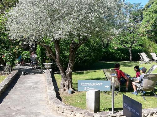 people sitting in chairs under a tree in a park at Logis Hôtel Château De Palaja in Carcassonne