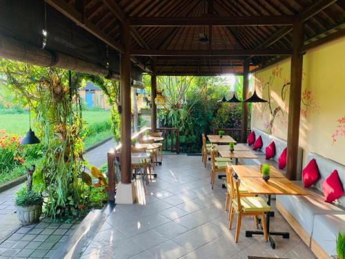 a restaurant with wooden tables and benches and plants at Villa D'Uma in Ubud