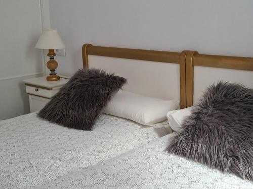 a bed with two fuzzy pillows on top of it at 1930 Diecinueve Treinta "Diseño, historia y confort en el centro de Gijón" in Gijón