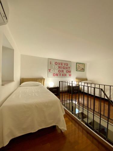 a white bedroom with a bed and a balcony at La Via della Giudecca in Siracusa