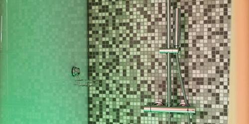 a bathroom with a shower with green and brown tiles at Hotel The Cube in Fidenza