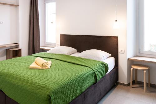 a bedroom with a bed with a green blanket at Hostel Museum in Koper