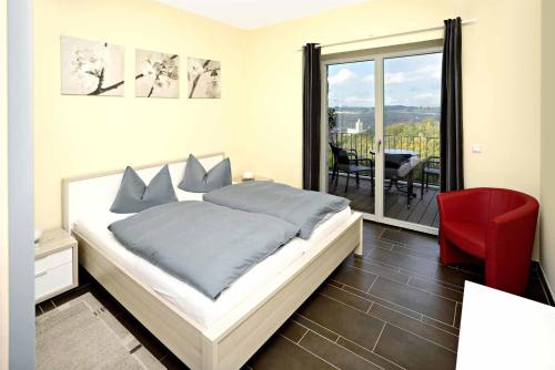 a bedroom with a bed and a red chair and a balcony at Hotel und Restaurant Rittergut Kreipitzsch in Naumburg