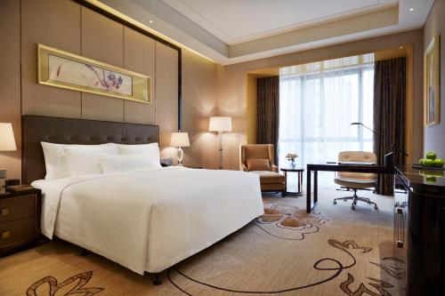a bedroom with a large white bed and a desk at Wanda Realm Beijing in Beijing