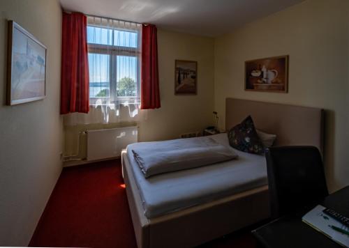 a bedroom with a bed and a window with red curtains at Waldhaus Jakob in Konstanz