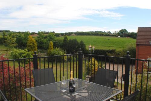 a glass table with a bottle of wine on a balcony at FAIRVIEW FARM Holiday Accommodation 14 Luxury Lodges, Cabins, Dog Friendly, Suitable for Couples, Families and Groups, Wedding Guests , Corporate events, Sleeps 2-65 guests in Ravenshead, Nottingham near Sherwood Forest, set in 88 acres in Nottingham