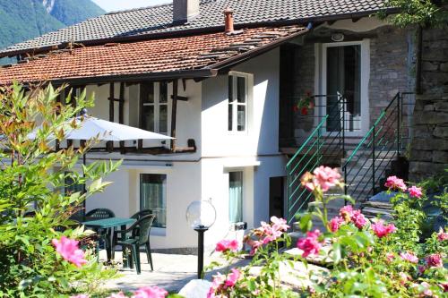 a white house with a table and chairs and flowers at Rivacanze Apartments in Laglio