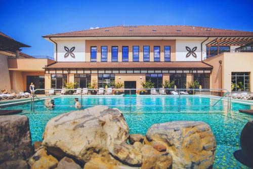 a swimming pool with rocks in front of a building at Caramell Premium Resort Superior in Bük