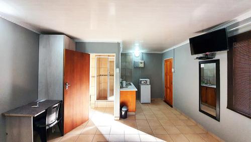 a room with a kitchen and a room with a table at Genesis Self Catering Apartments in Bloemfontein