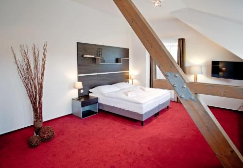 a bedroom with a white bed and a red carpet at Hotel Zámecká Sýpka in Blansko