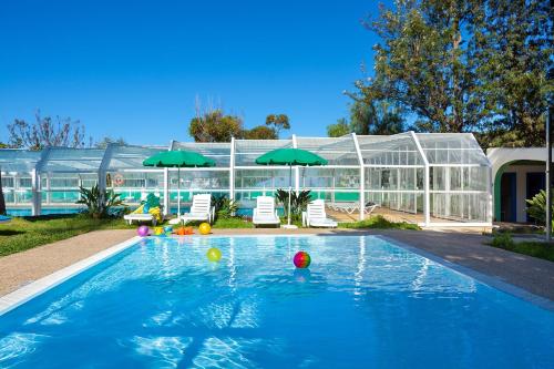 a swimming pool with umbrellas in front of a glass house at Parque Vacacional Eden in Puerto de la Cruz