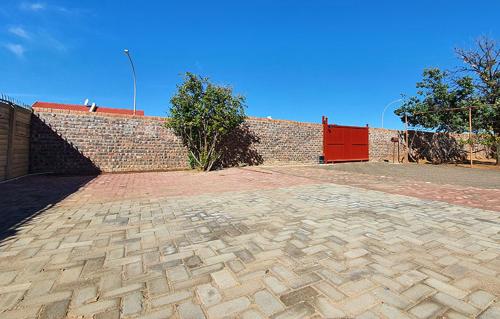 a brick wall with a red door and a brick patio at Genesis Self Catering Apartments in Bloemfontein