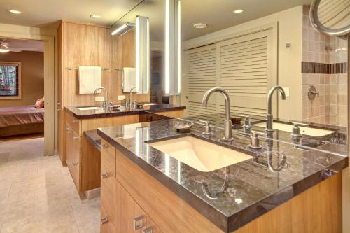 a bathroom with two sinks and two mirrors at Makena Surf- CoralTree Residence Collection in Wailea