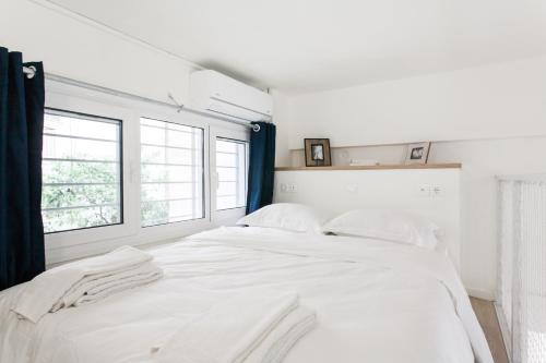 białe łóżko w pokoju z 2 oknami w obiekcie Be based in this groovy loft in the CITY CENTER!! w Atenach
