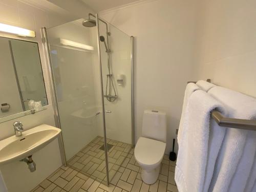 a bathroom with a shower and a toilet and a sink at Hotell Koselig in Kyrksæterøra