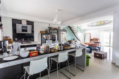 een keuken met een aanrecht met witte stoelen en een aanrechtblad bij The Maverick Surfvillas in Lourinhã