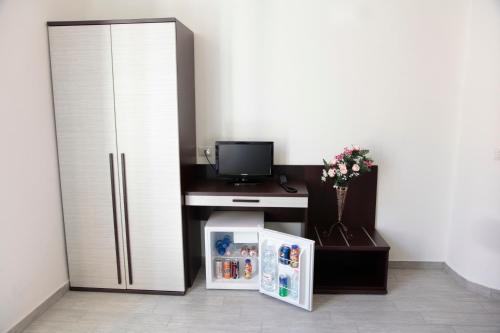 Zimmer mit einem Kühlschrank und einem Schreibtisch mit einem TV. in der Unterkunft HOTEL Poma in Mailand