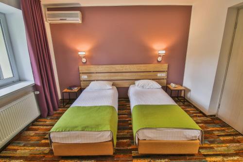 two beds in a small room with green sheets at Ukraina Hotel in Cherkasy