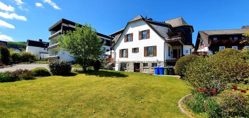 a large white house with a grass yard at Sevda's Hotel Garni Weinforth in Willingen