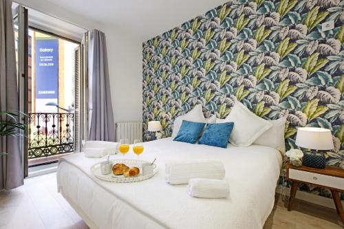 a bedroom with a large bed with a floral wall at Callao One in Madrid