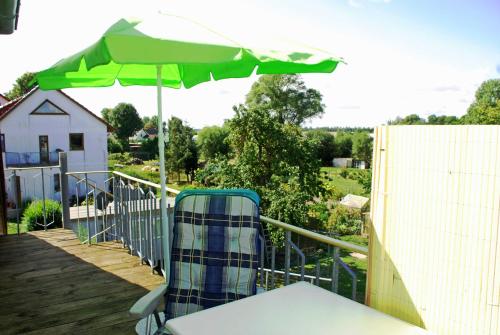 a green umbrella and a chair on a deck at Ferienwohnung Familie Schoenemann in Patzig