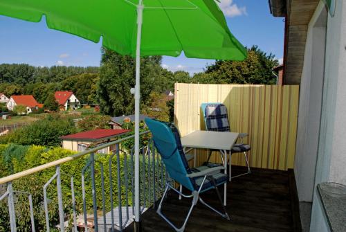 a green umbrella and two chairs and a table on a balcony at Ferienwohnung Familie Schoenemann in Patzig