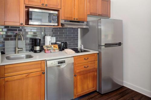 a kitchen with a stainless steel refrigerator and wooden cabinets at Hyatt House Parsippany East in Parsippany