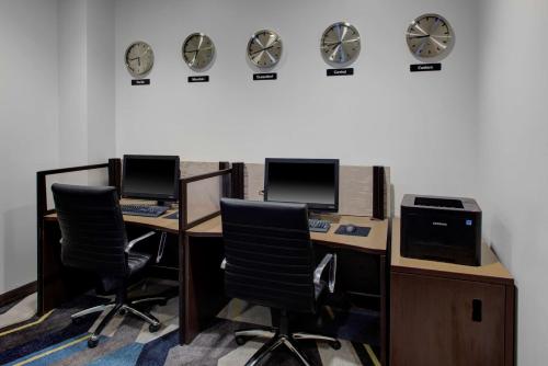 an office with two desks with chairs and clocks on the wall at Hyatt House Raleigh Durham Airport in Morrisville
