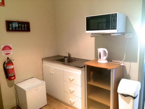 una pequeña cocina con fregadero y microondas en Guesthouse 83, en Cronulla