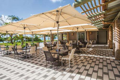 a patio with tables and chairs with umbrellas at Crystals Beach Resort Belle Mare, a member of Radisson Individuals in Belle Mare