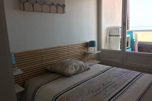 ein Bett in einem Schlafzimmer mit einem großen Fenster in der Unterkunft Appartement T2 avec vue sur mer directe ! in Courseulles-sur-Mer