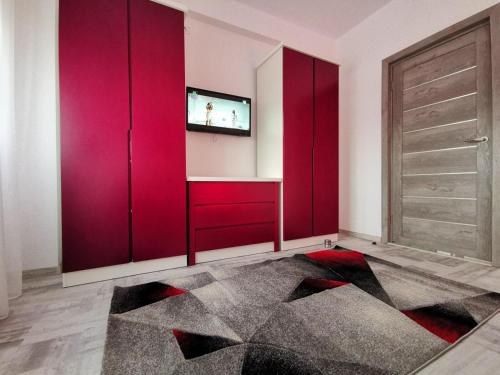ein Wohnzimmer mit roten Schränken und einem TV in der Unterkunft Violet Apartment-Brilliant Apartments in Constanţa