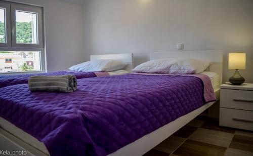 ein Bett mit einer lila Bettdecke in einem Schlafzimmer in der Unterkunft Galeb 2 in Veli Iž