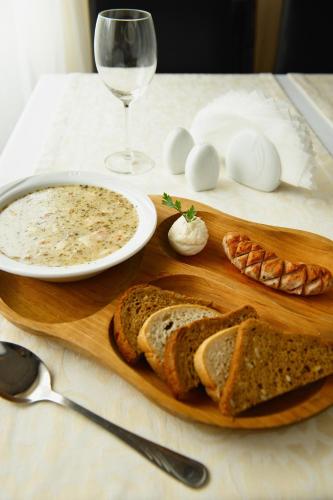 a wooden board with bread and a plate of soup and a glass of wine at Hotel Marina in Nielisz