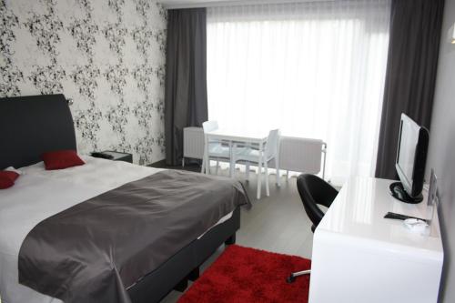 a bedroom with a bed and a desk with a television at Hotel Panorama in Overijse