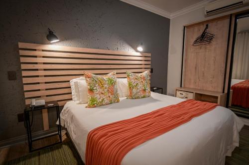 a bedroom with a large bed with a wooden headboard at Villa Bali Luxury Guesthouse in Bloemfontein