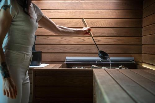 a woman is standing next to a grill with a spatula at Castel Hörtenberg in Bolzano