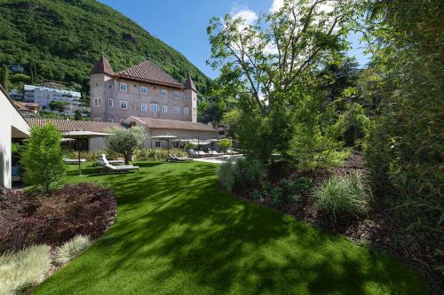 a green yard with a large building in the background at Castel Hörtenberg in Bolzano