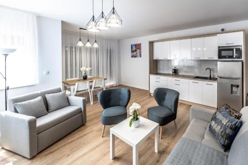 ein Wohnzimmer mit einem Sofa und Stühlen sowie eine Küche in der Unterkunft Apartament Margo in Łeba