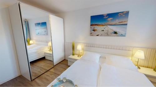 ペルツァーハケンにあるVilla Meeresrauschen Meerblick 6aの白いベッドルーム(ベッド2台、鏡付)
