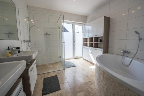 a white bathroom with a tub and a sink at Ferienwohnungen Ebenzweier in Altmünster