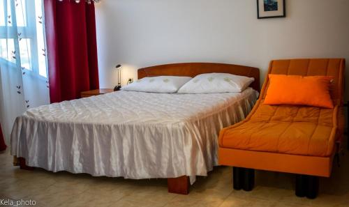 ein Bett mit einem orangenen Stuhl in einem Schlafzimmer in der Unterkunft Galeb 3 in Veli Iž