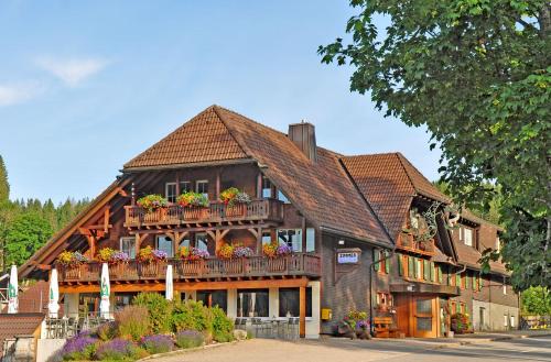 ein Holzhaus mit einem Balkon mit Blumen darauf in der Unterkunft Hotel Hirschen in Schluchsee
