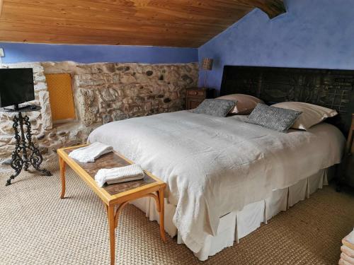 1 dormitorio con 1 cama grande y pared de piedra en Maison Basta, en Orthevielle